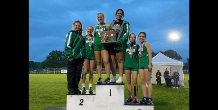 Mogadore girls track team on podium holding division championship trophy.